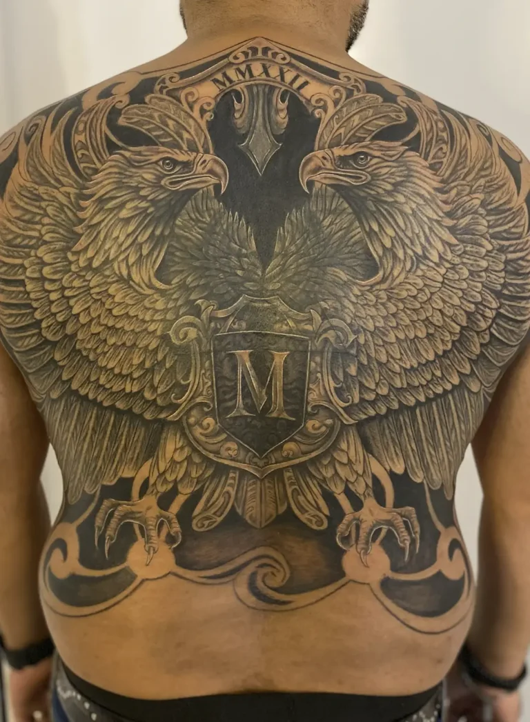 Tatuaje cover up en la espalda con diseño de águilas reales en negro y gris, por la artista Angélica Nicoletti de Kamba Tattoo.